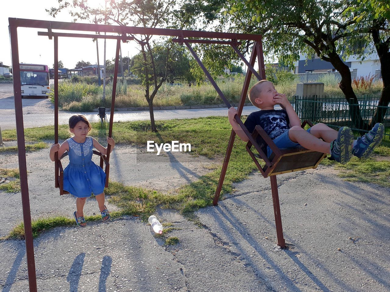 Siblings playing on swings in park