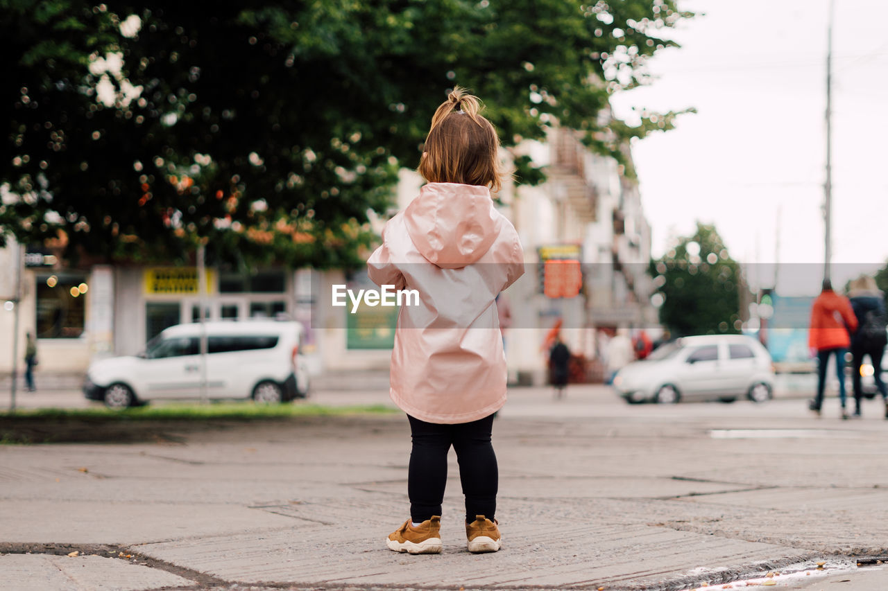 Rear view of girl standing on road