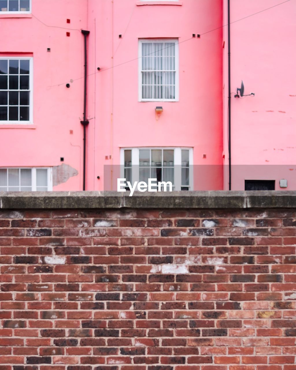 Brick wall against pink building in city