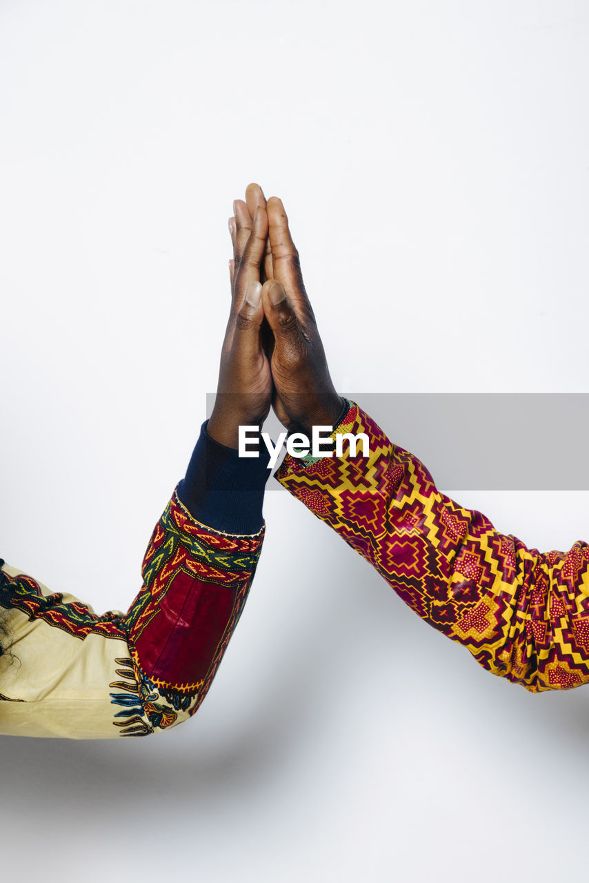 Closeup shot of anonymous couple in trendy african outfit standing on white background in studio