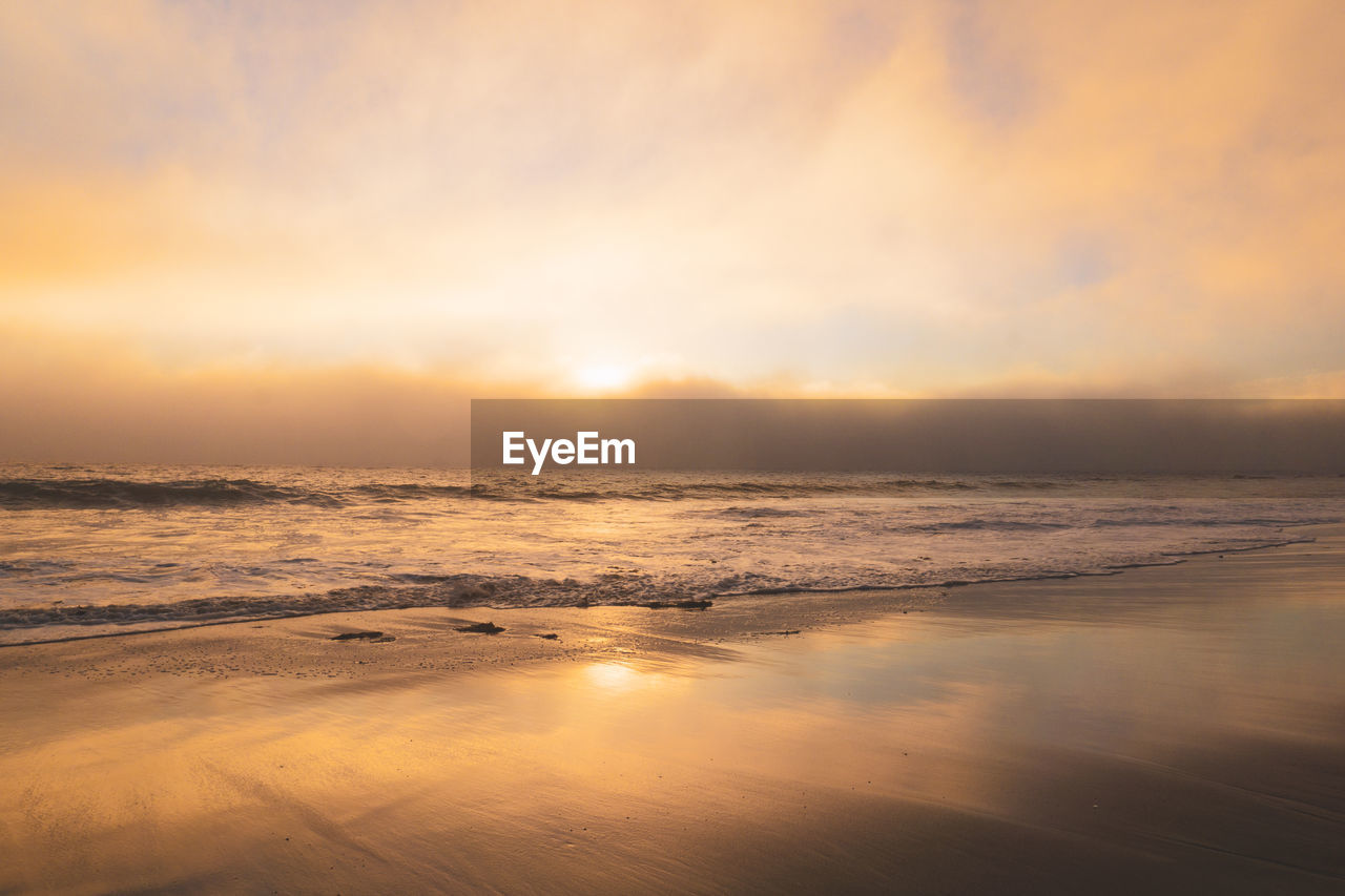 Beach sunset with marine layer clouds moving in creating a golden glow and  a misterious feeling