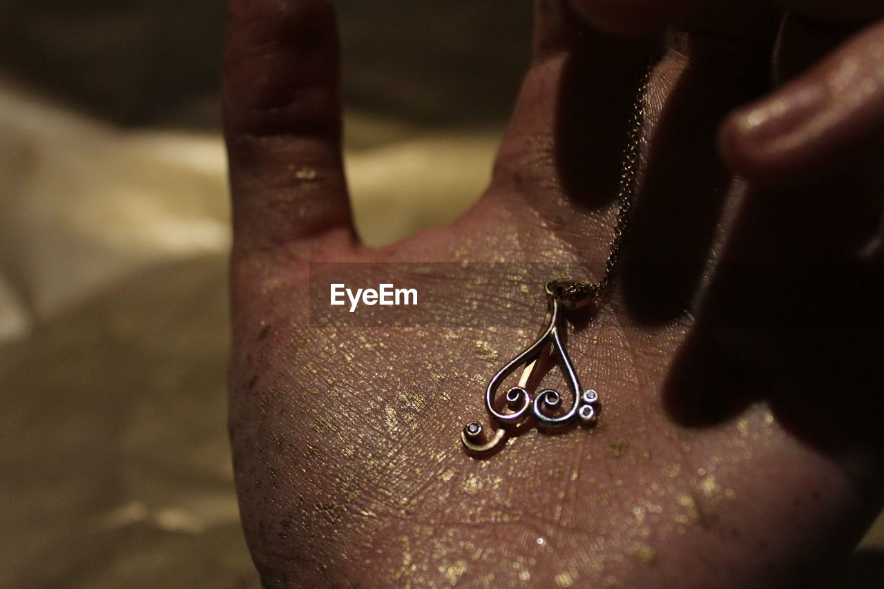 Cropped hand of woman holding heart shape locket