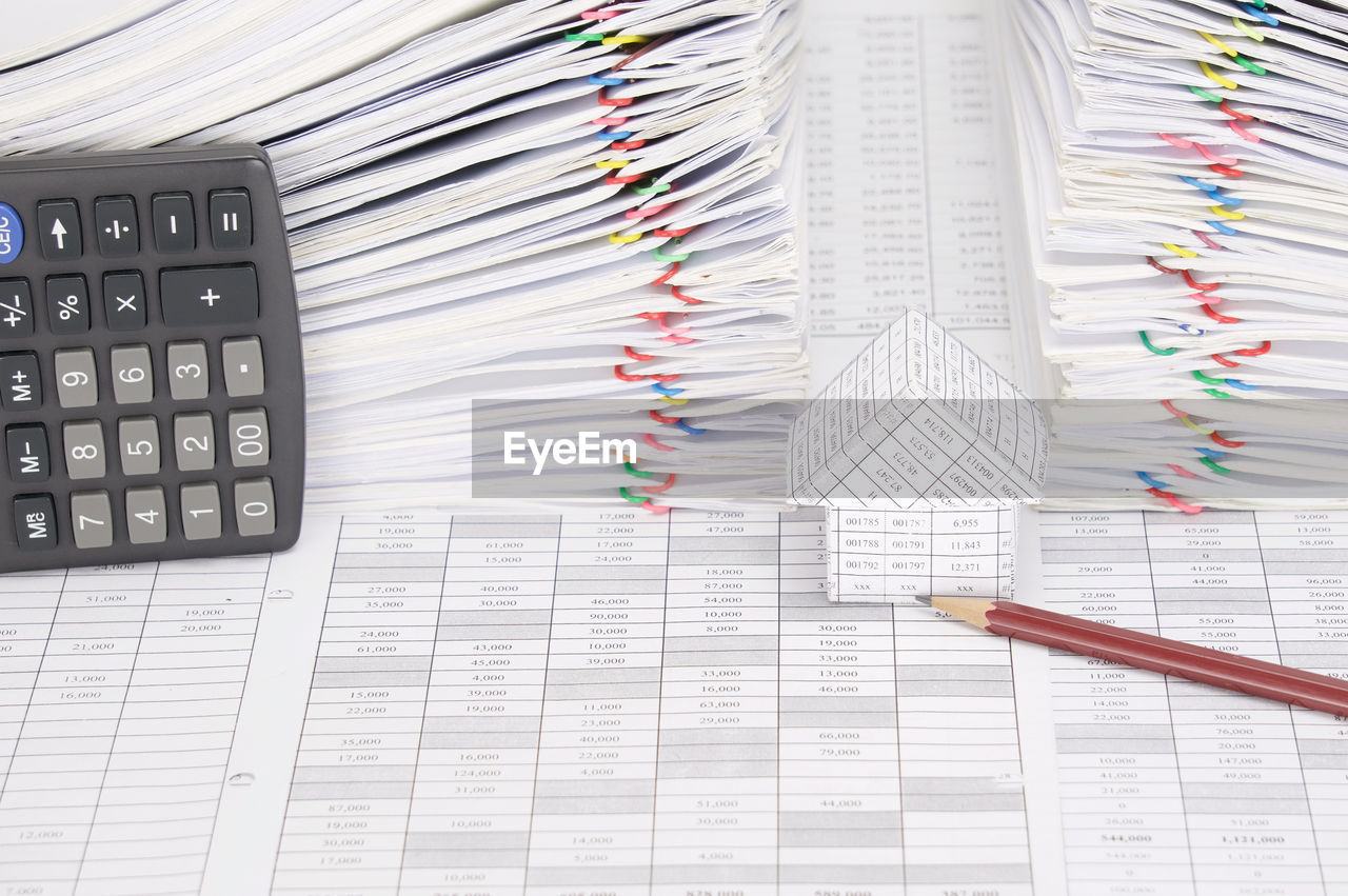 High angle view of model house with pencil and calculator on financial documents