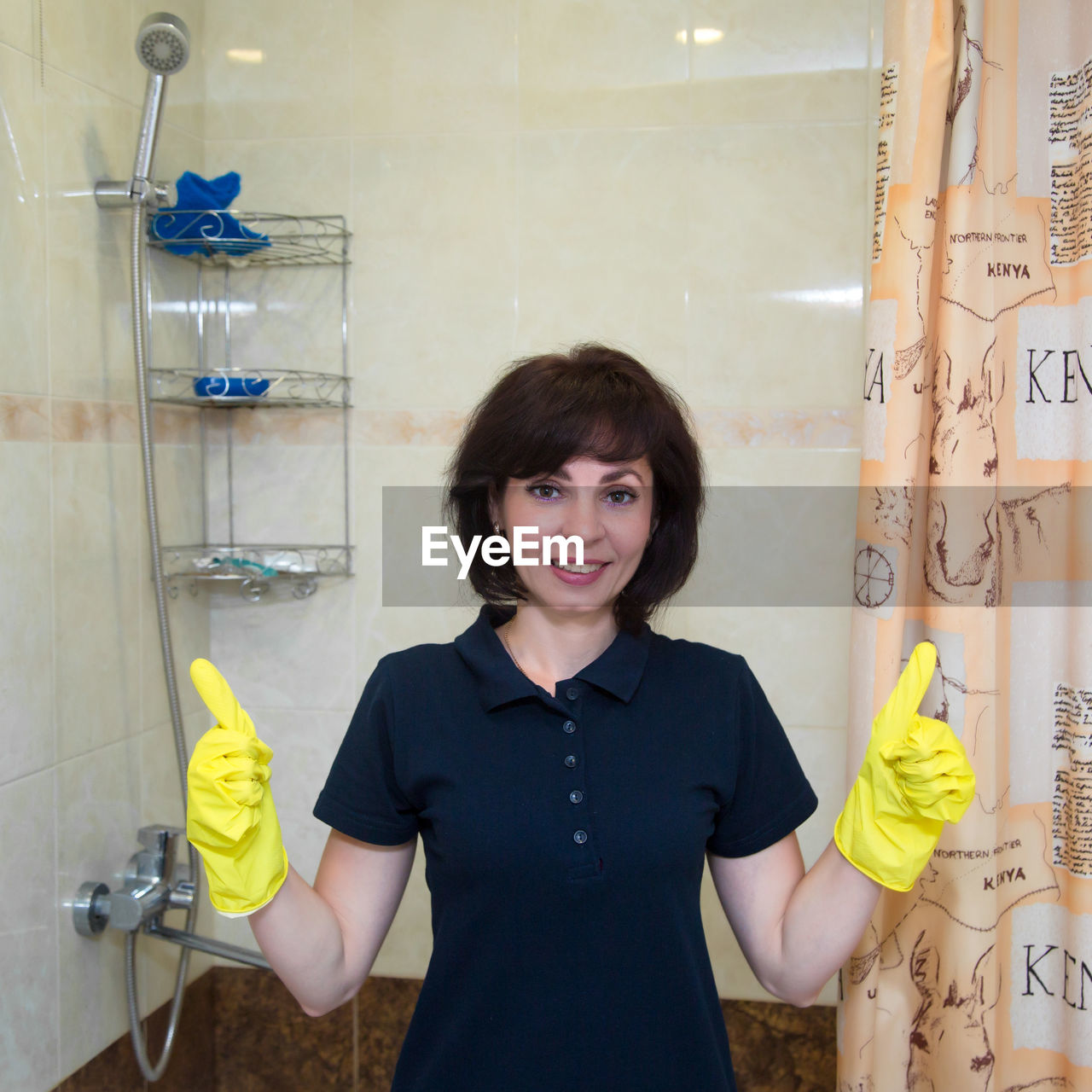 one person, indoors, women, looking at camera, portrait, bathroom, adult, smiling, occupation, cleaning, female, protective glove, standing, front view, sink, working, waist up, protective workwear, emotion, washing up glove, domestic room, hygiene, clothing, protection, cleanliness, home, person, happiness, holding, brown hair, yellow, domestic life, business