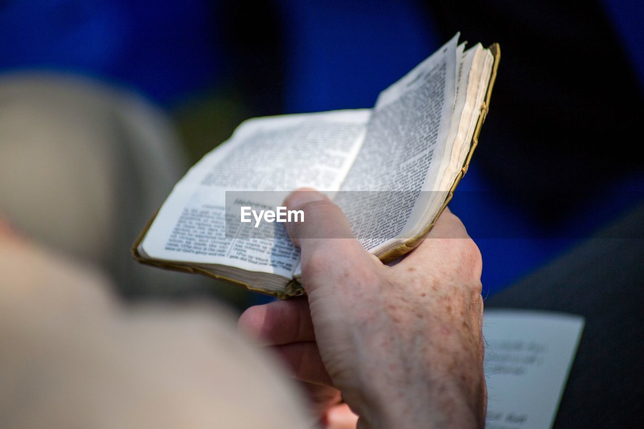 CLOSE-UP OF HAND HOLDING BOOK WITH PAPER