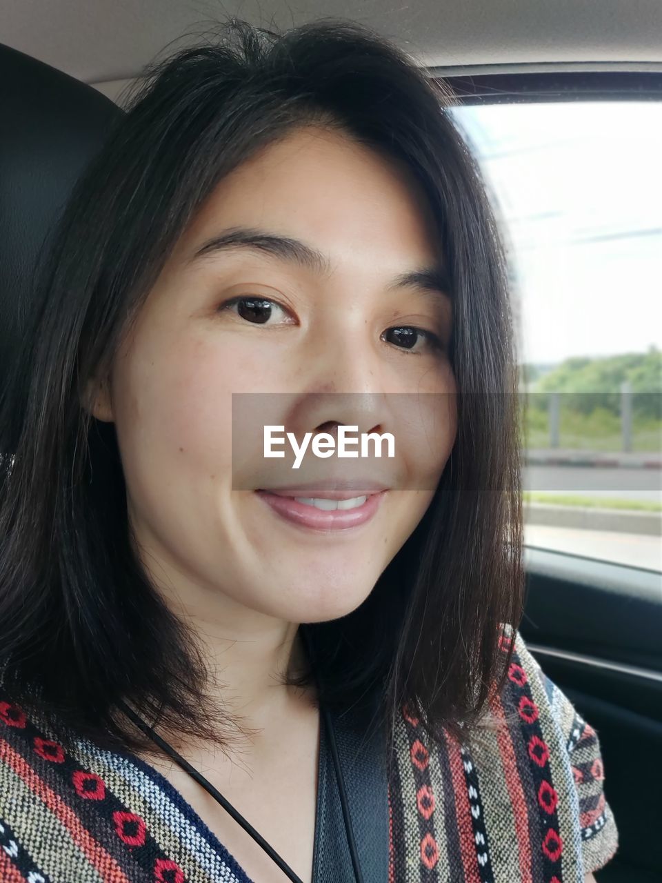 PORTRAIT OF A SMILING YOUNG WOMAN IN CAR