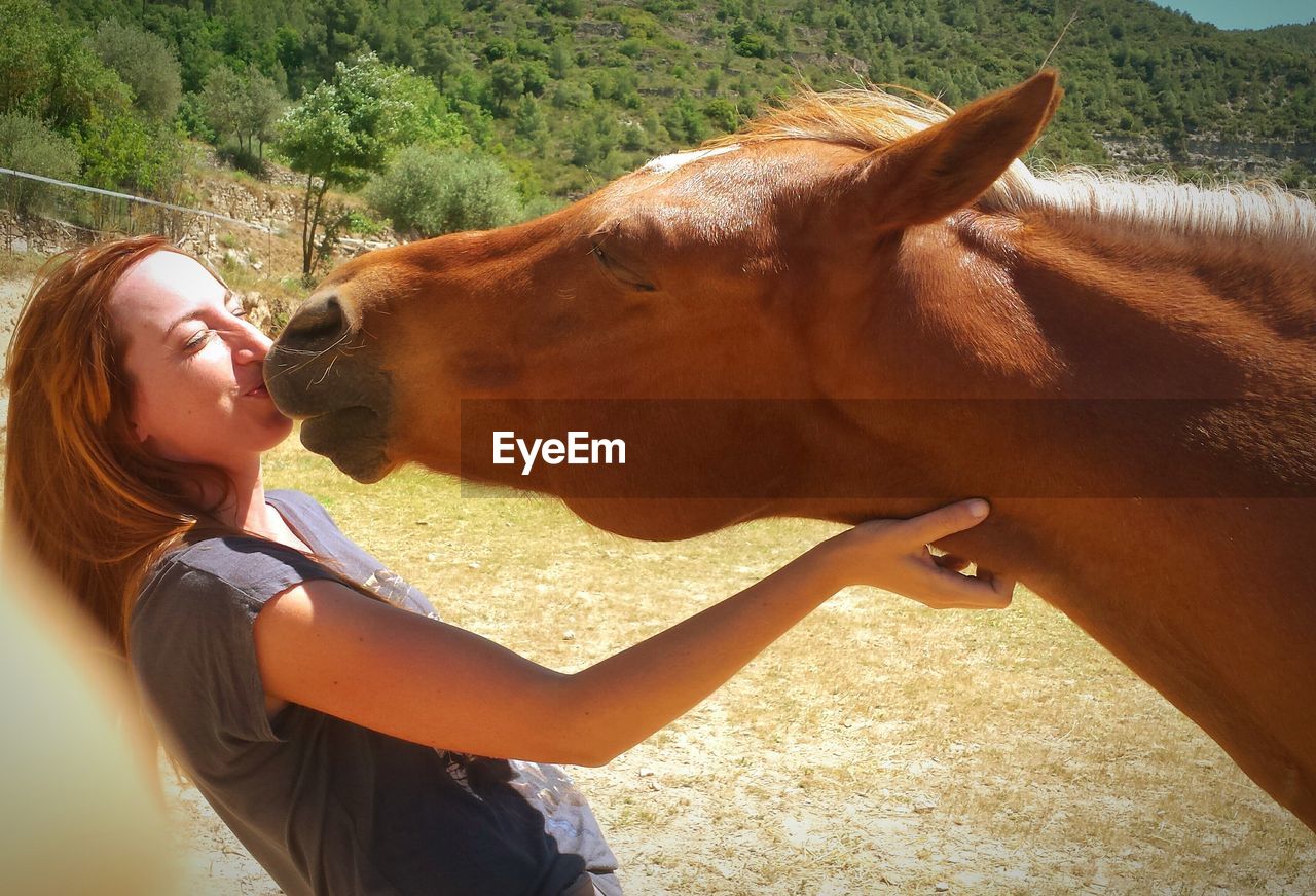 Woman kissing horse outdoors