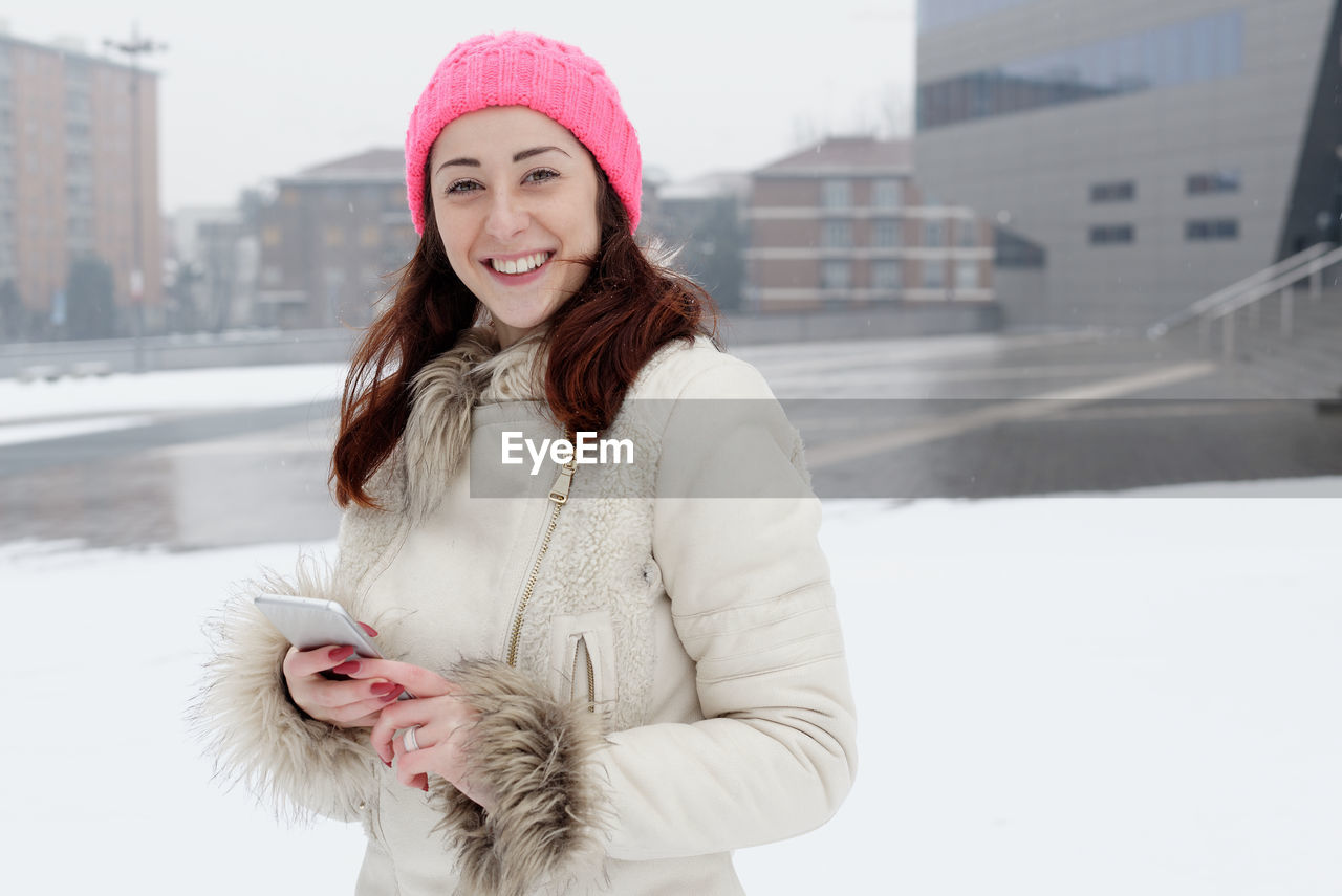 Portrait of smiling young woman standing in snow