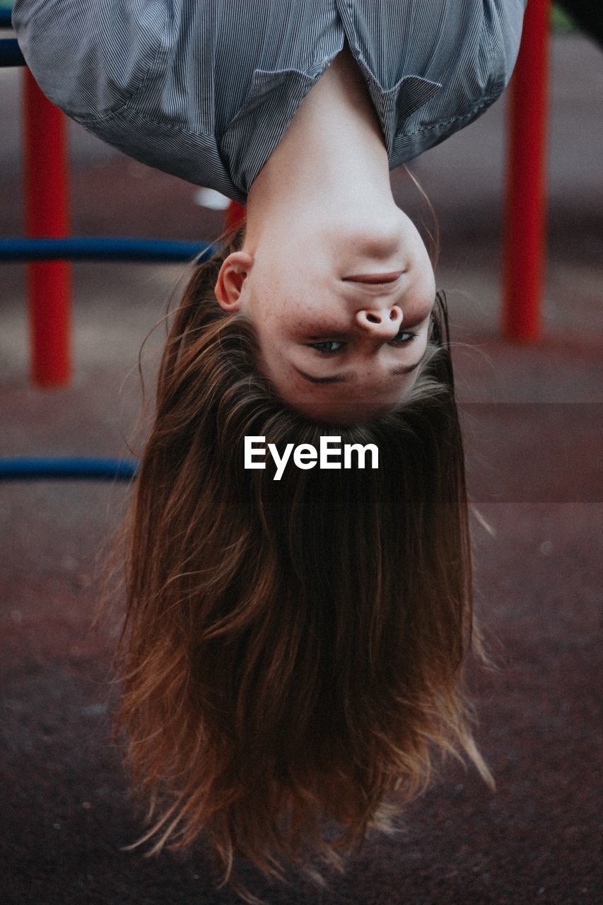 Portrait of woman hanging upside down in playground