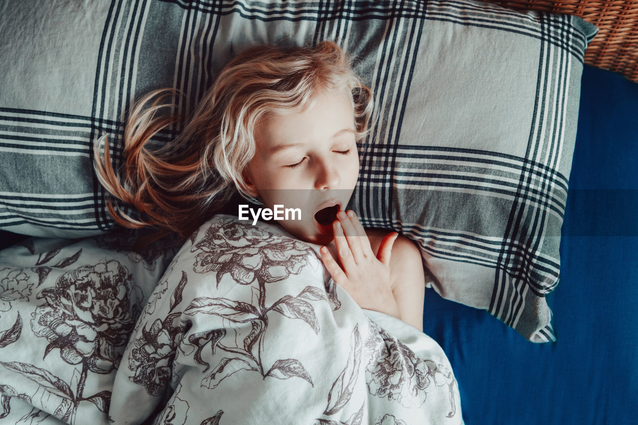 Child girl sleeping yawning in bed at home. sweet dreams. everyday routine in the morning. 