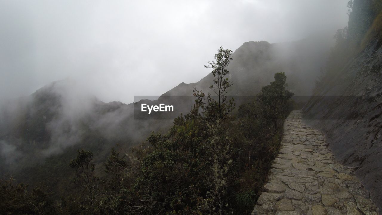 SCENIC VIEW OF MOUNTAINS IN FOGGY WEATHER AGAINST SKY