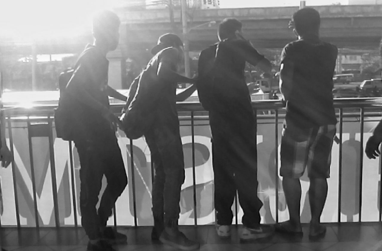 Rear view of friends standing by railing