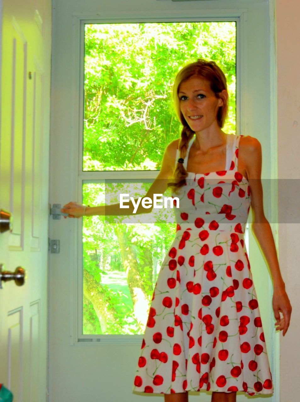 Smiling young woman standing by door at home