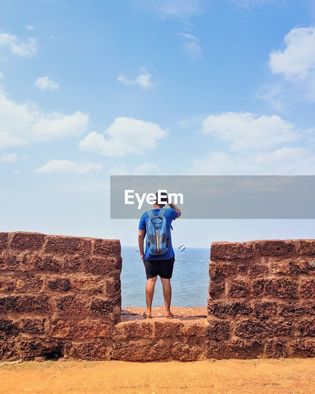 REAR VIEW OF WOMAN STANDING ON ROCKS