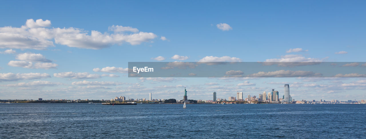 Sea by cityscape against sky