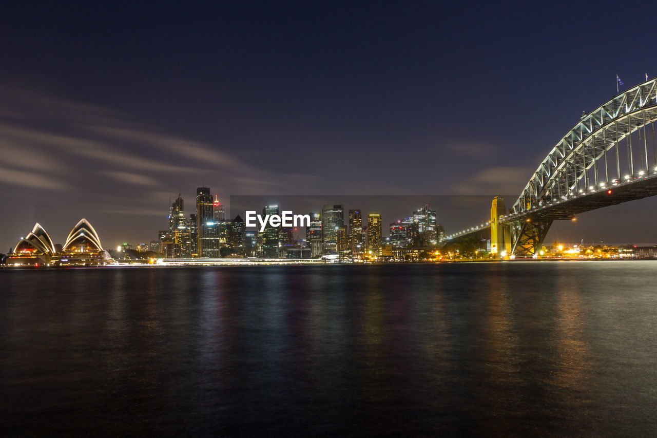 Illuminated bridge and cityscape against sky at night