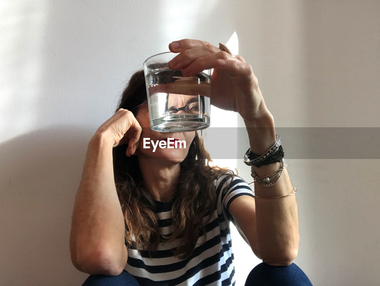 PORTRAIT OF YOUNG WOMAN HOLDING SUNGLASSES AT HOME