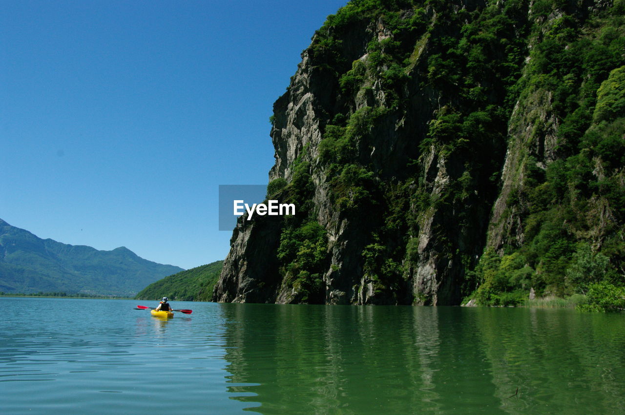 Person kayaking in lake against sky