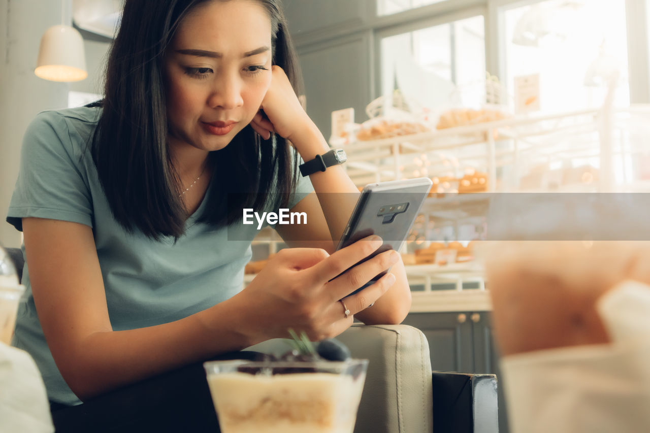 Young woman using mobile phone in cafe