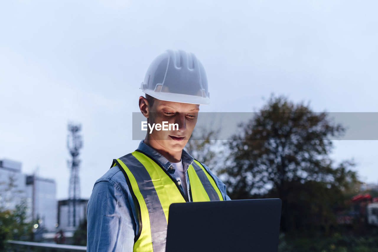 Engineer wearing hardhat using laptop