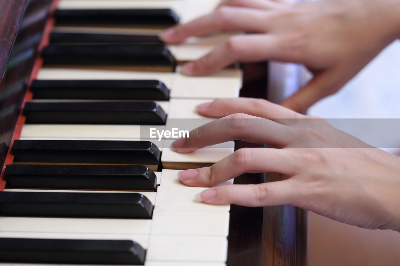 Cropped hands of woman playing piano