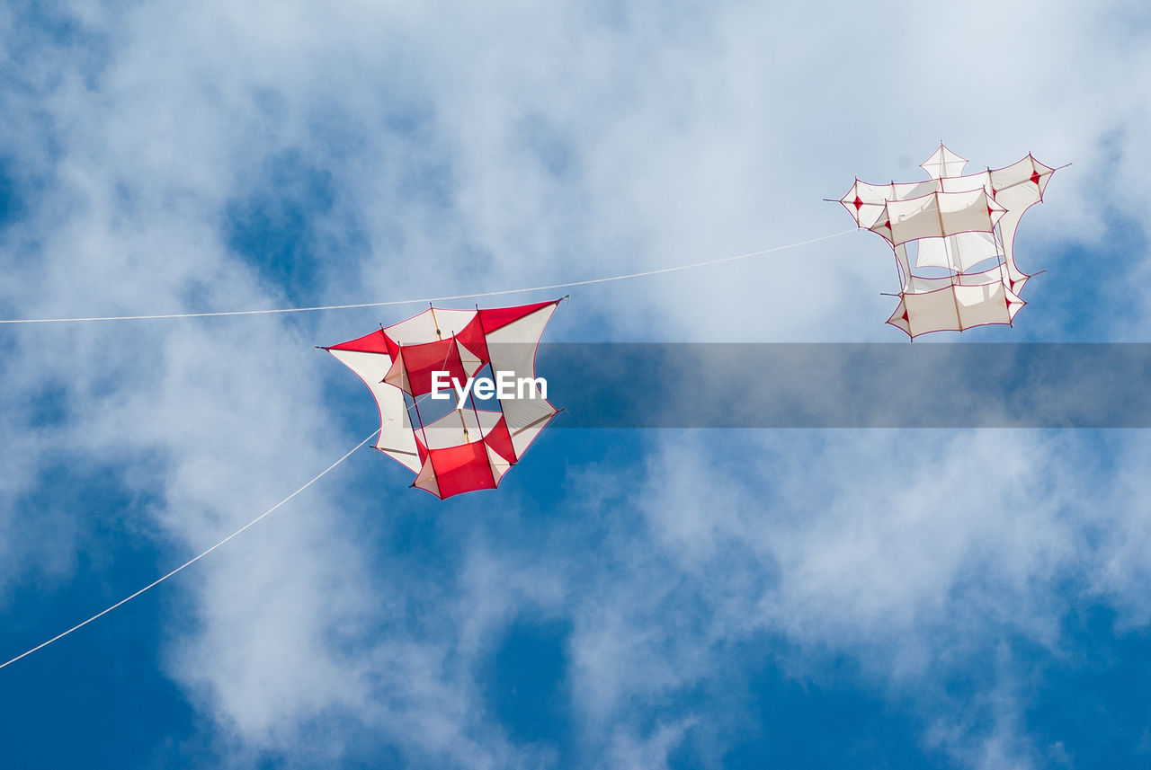 Low angle view of kites flying against sky