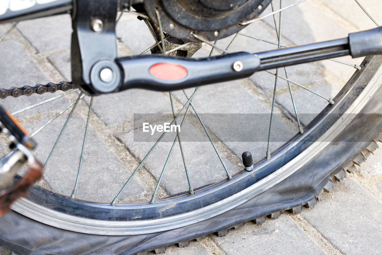 A punctured and flat bicycle tire on a background of gray paving slabs. closeup.