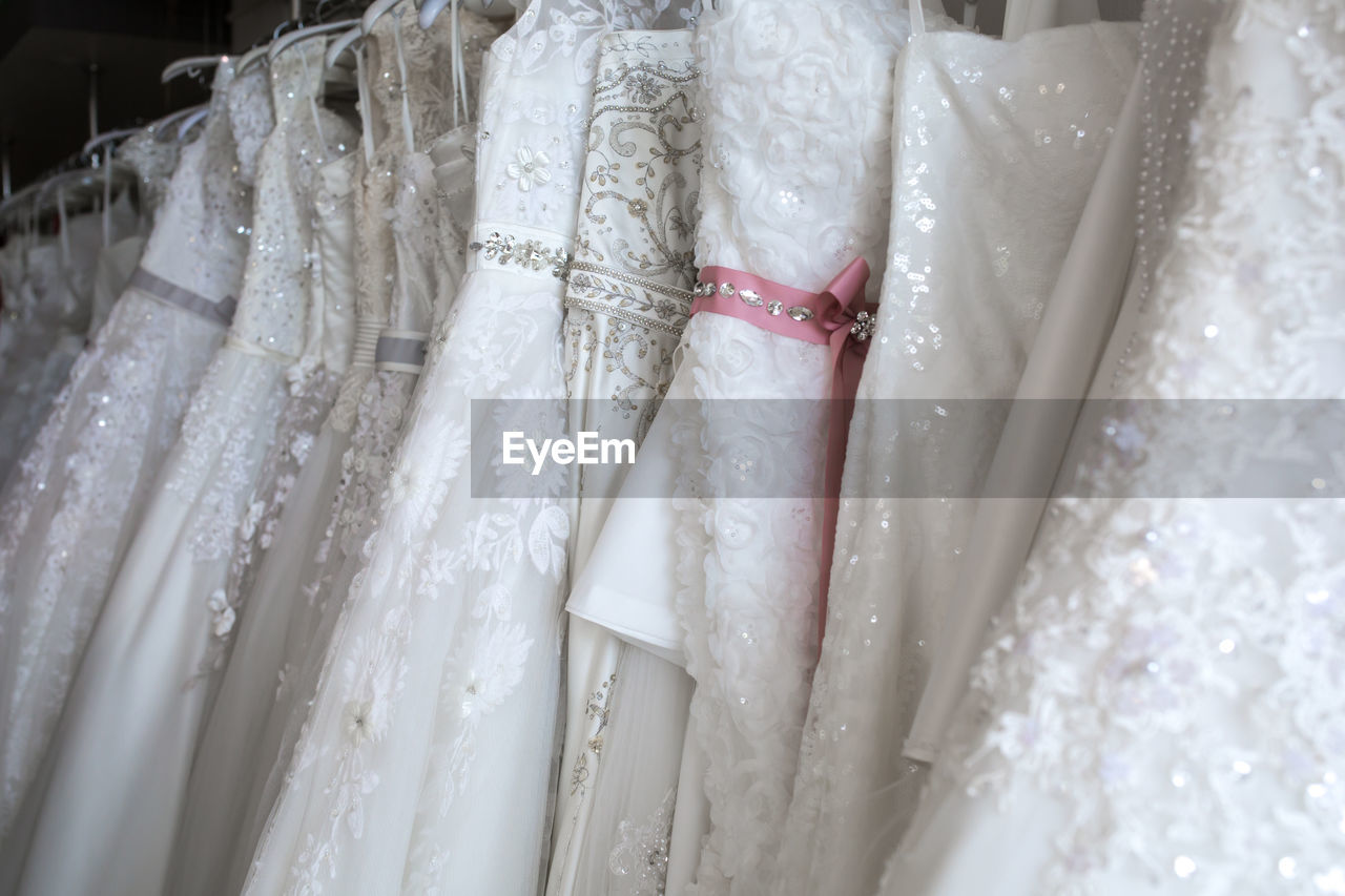 White dresses hanging in row for sale at clothing store