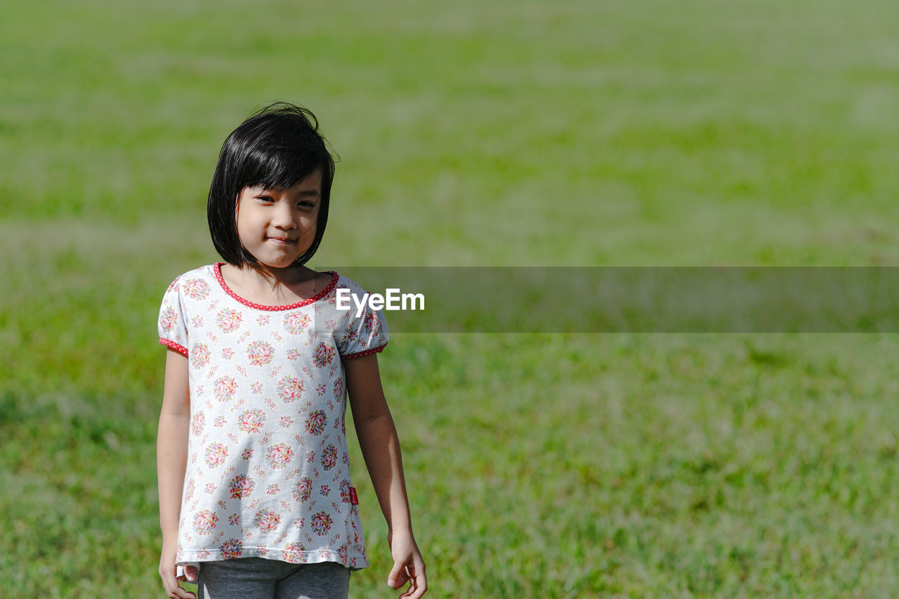 Portrait of smiling girl standing on field