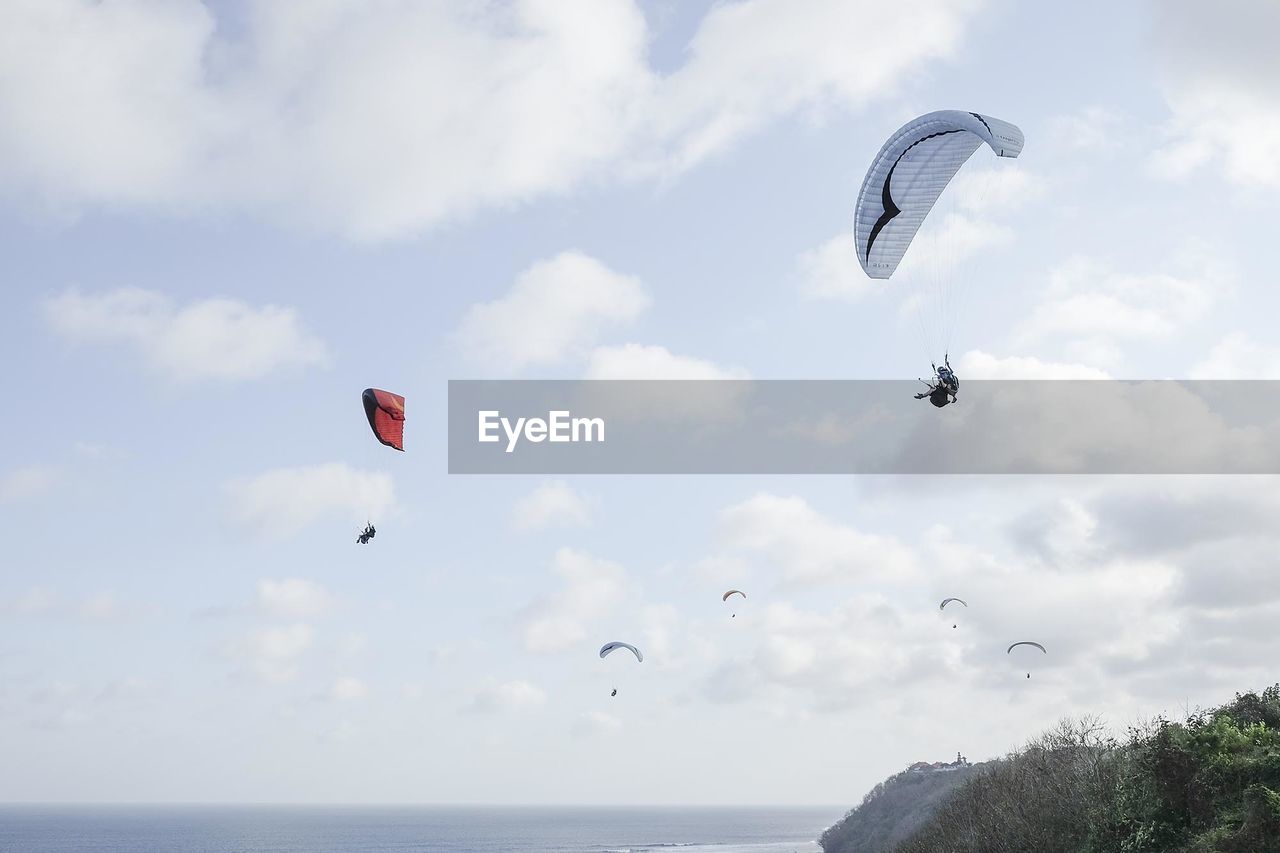 PEOPLE PARAGLIDING AGAINST SKY