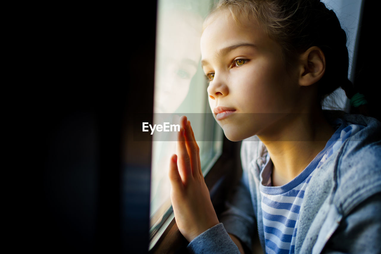 Close-up of girl looking away through window