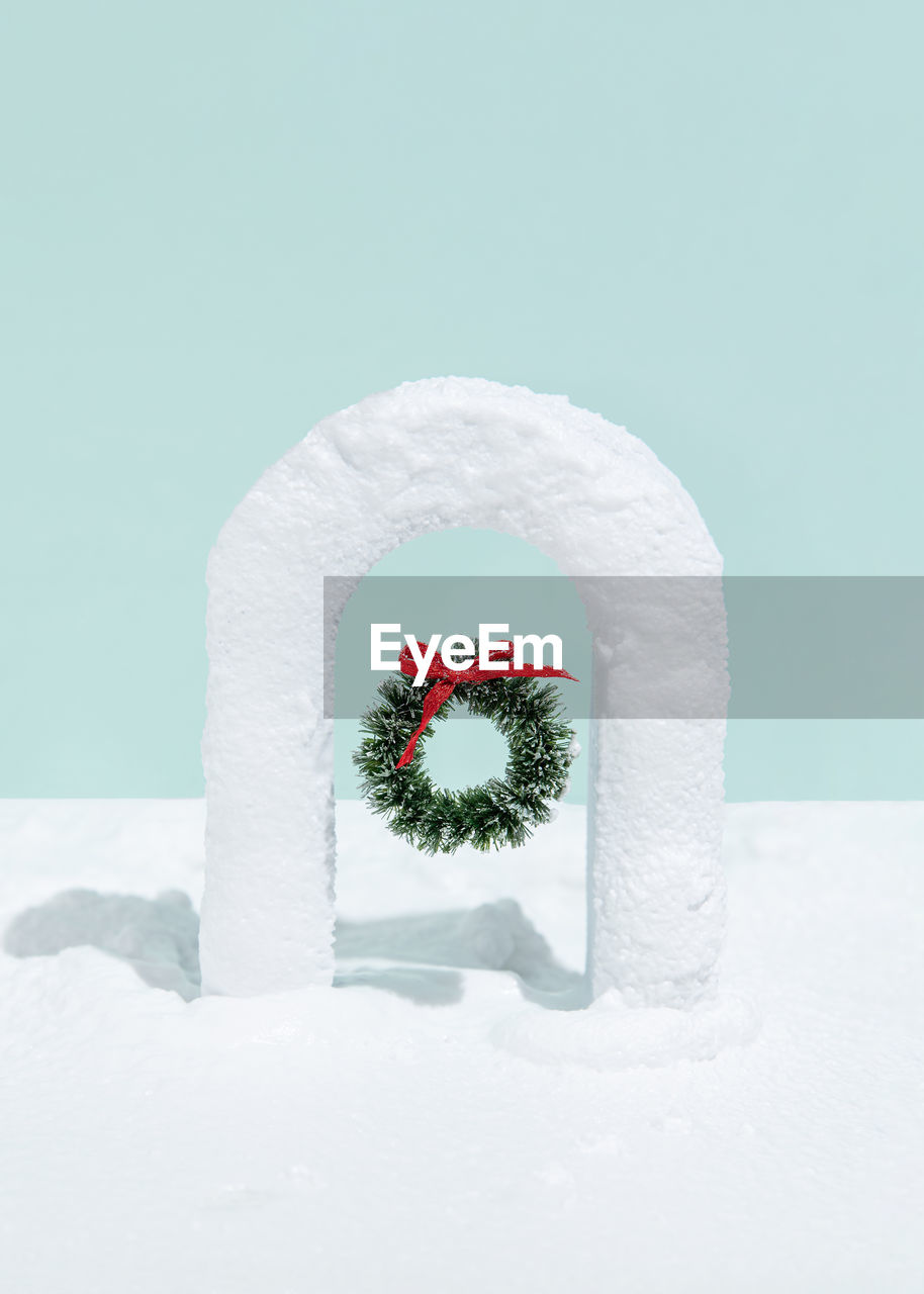 Christmas wreath in snow covered gate on blue background. minimal creative christmas concept.