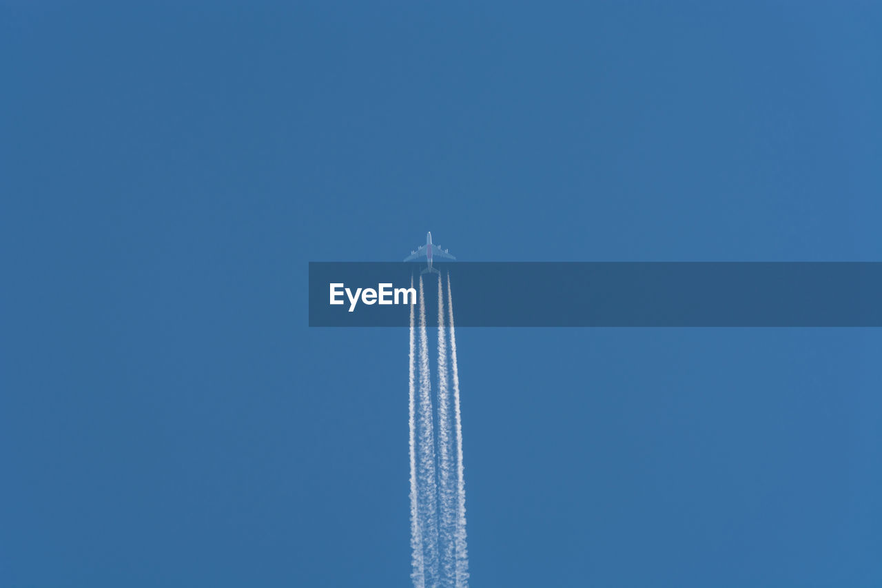 Low angle view of airplane flying against clear blue sky