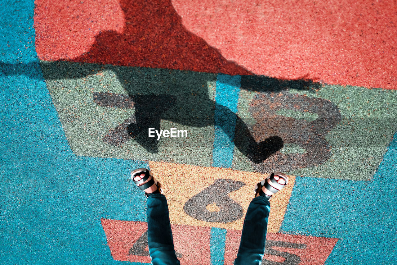 Low section of man standing on multi colored shadow