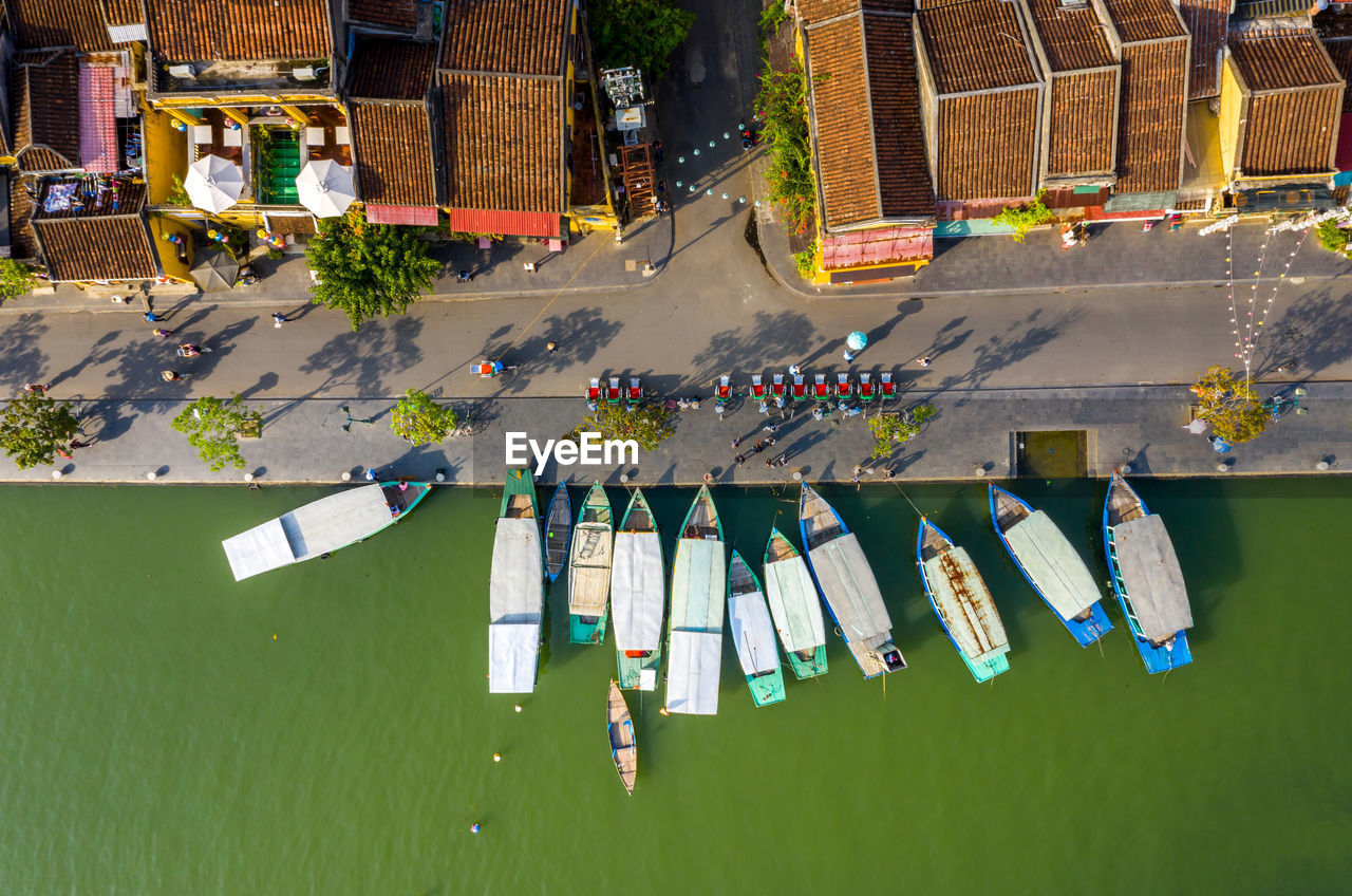Drone view of boats in river by buildings