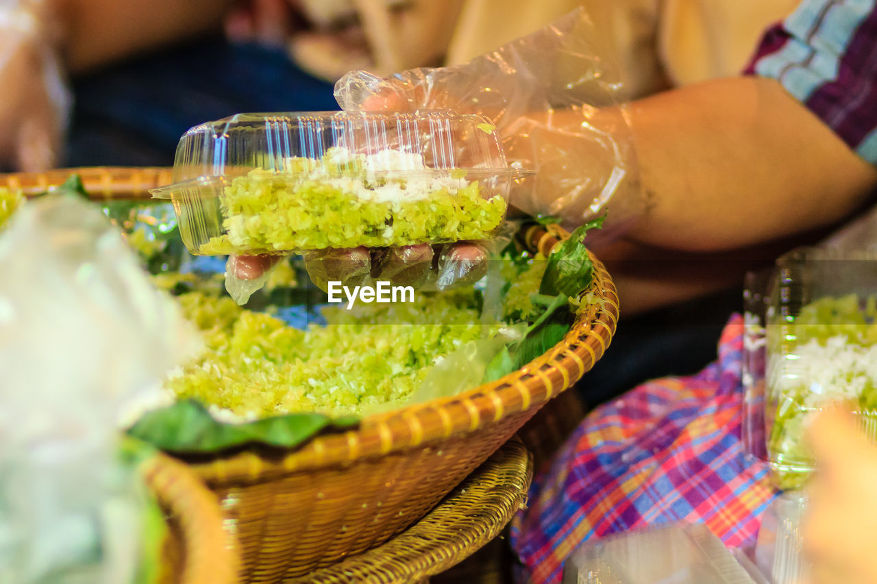 CLOSE-UP OF MAN PREPARING BASKET IN PLATE