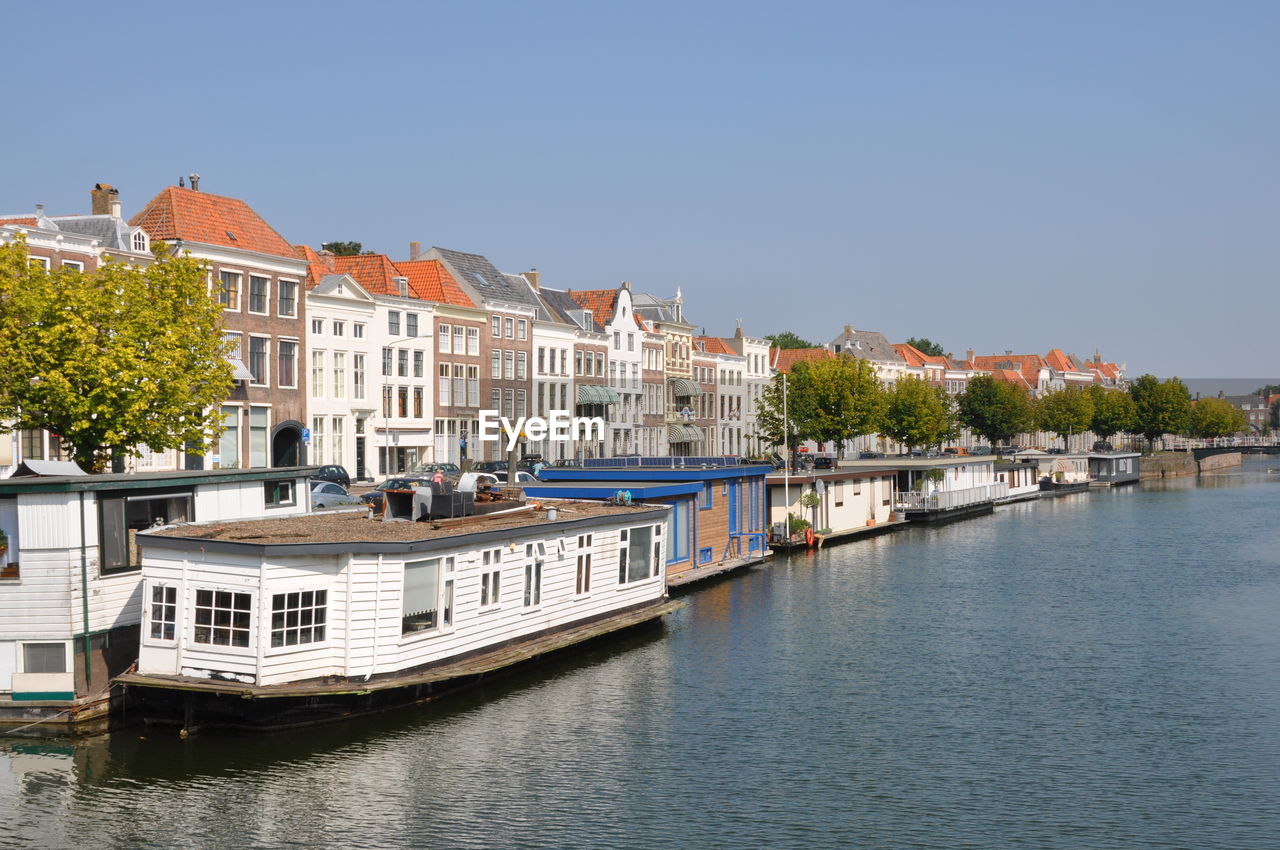 Buildings by river against clear sky