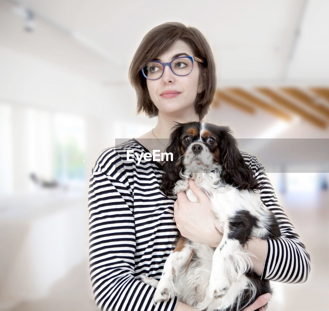 Woman holding dog while standing at home