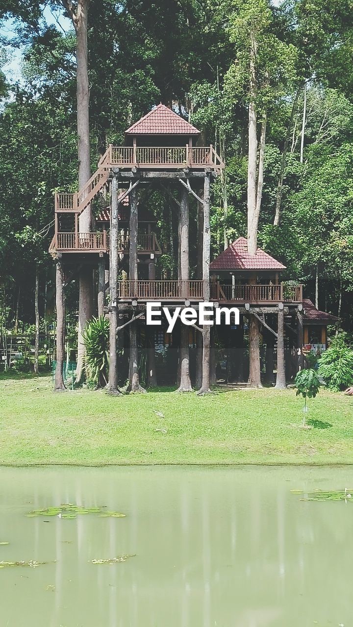 Lake in front of tree house against trees