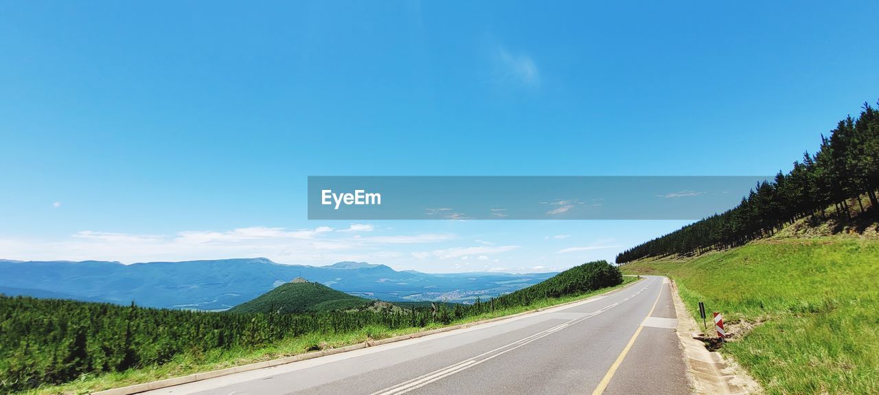 Empty road against clear blue sky