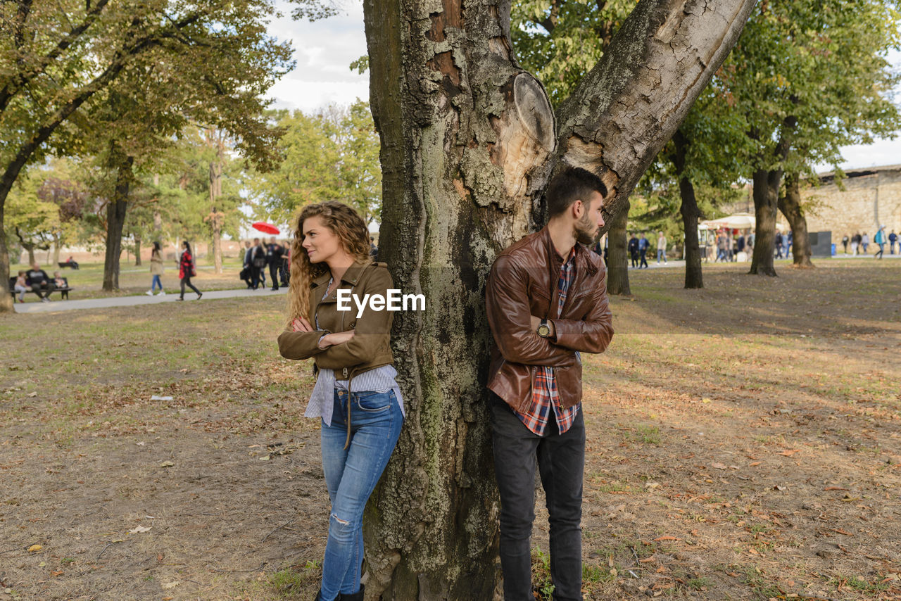 Angry couple standing against tree at park