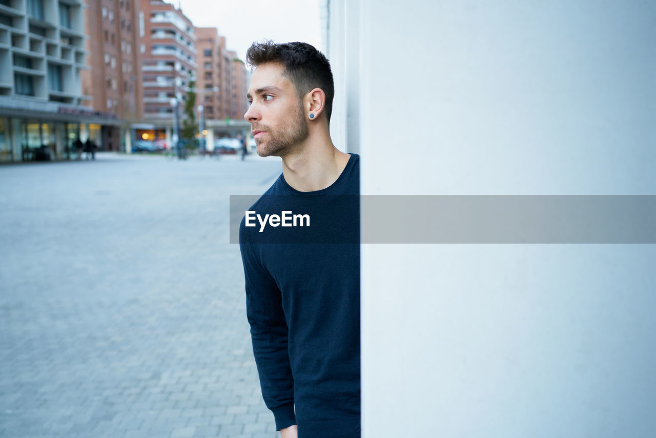 The modern man in casual clothes leaning against a wall