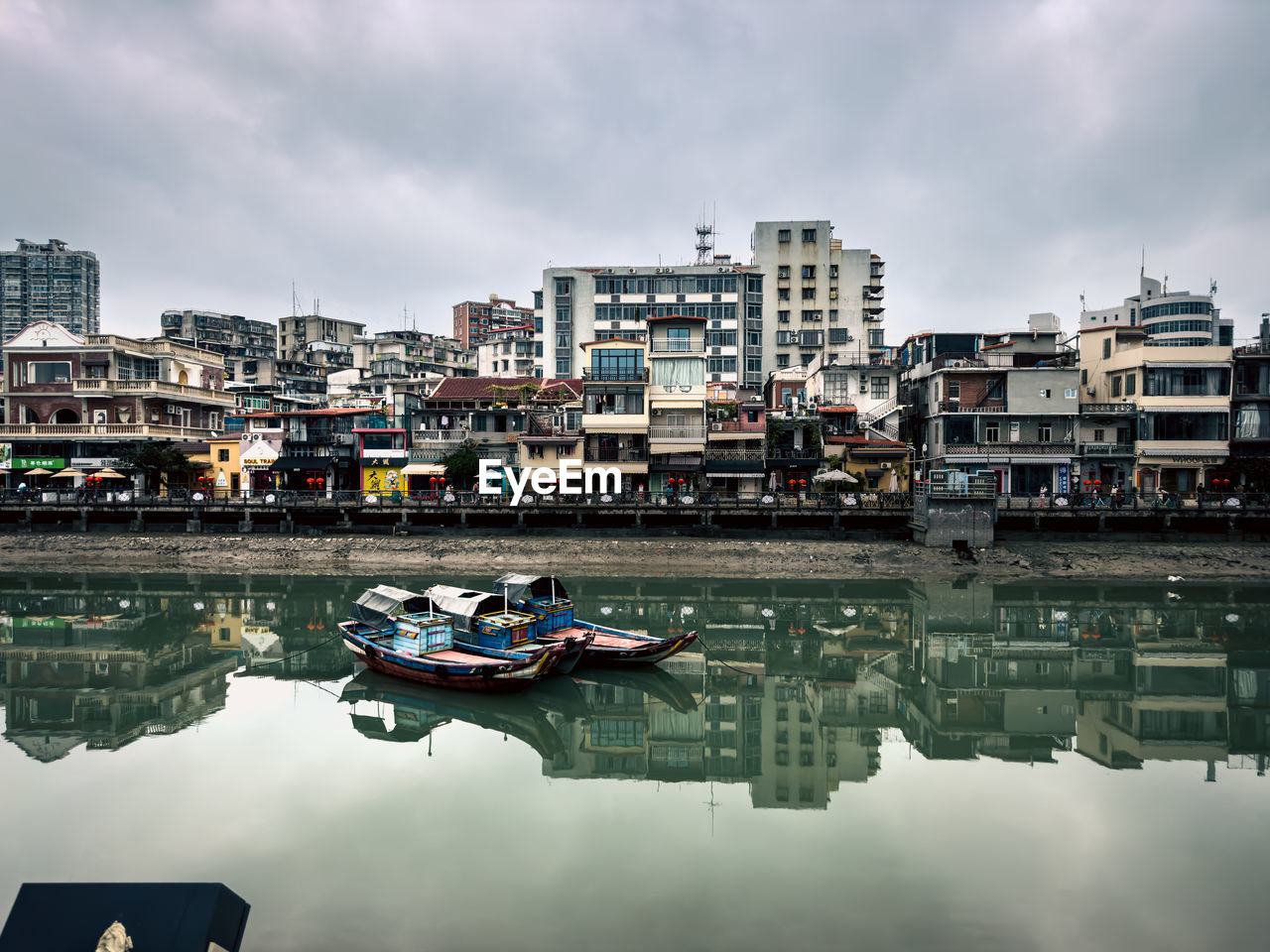 Boats in river against cloudy sky, retail street 