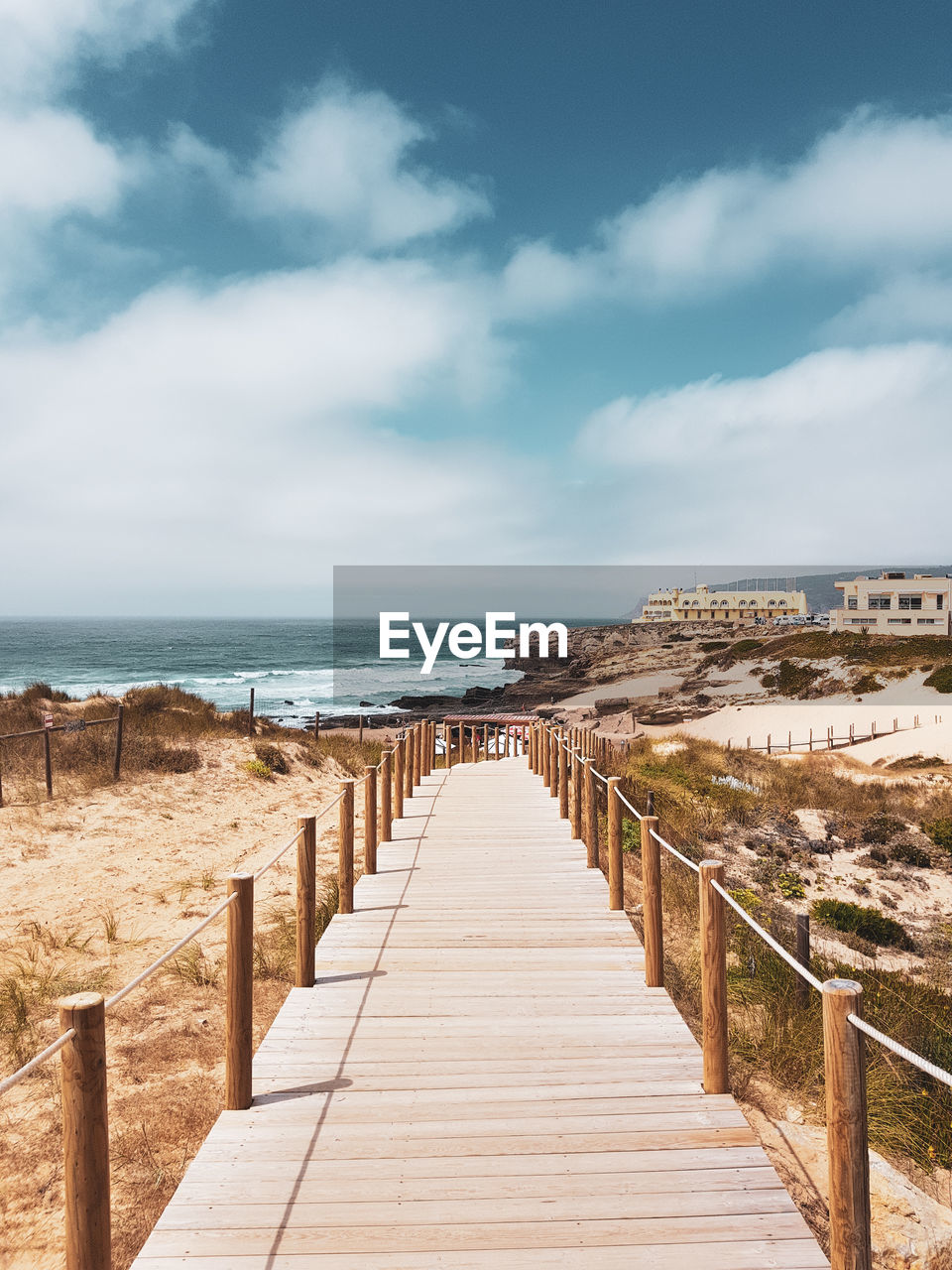 Boardwalk at beach against sky