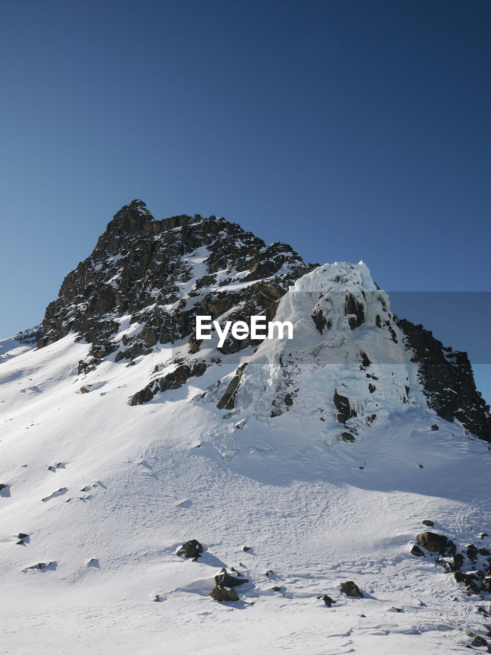 Scenic view of snow covered mountains against blue sky