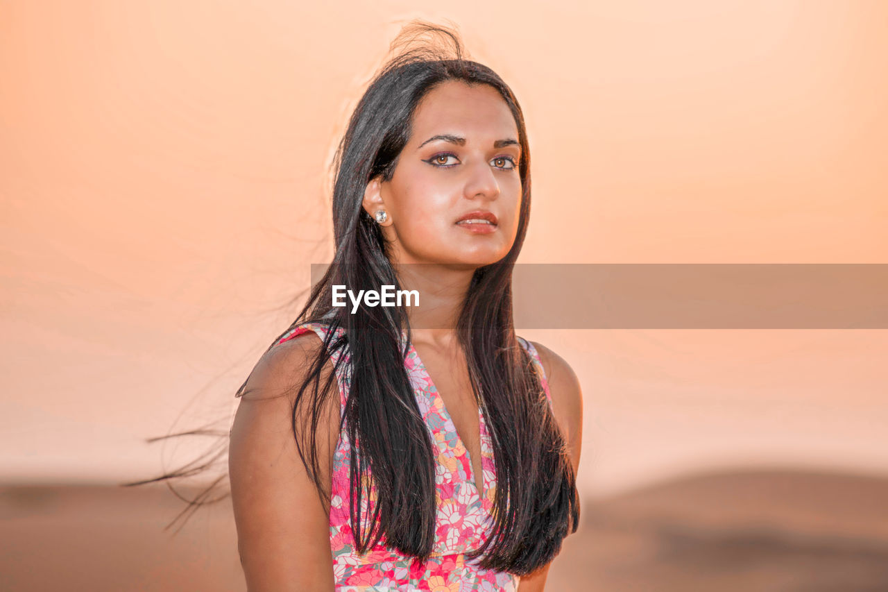 one person, long hair, portrait, women, hairstyle, adult, sunset, female, photo shoot, young adult, nature, land, brown hair, sky, smiling, looking at camera, fashion, copy space, clothing, portrait photography, teenager, emotion, standing, waist up, happiness, lifestyles, looking, beauty in nature, landscape, relaxation, outdoors, child, headshot, dress, summer, sunlight, skin, pink, person, environment, human face, contemplation, tranquility, travel, front view, vacation, serious, trip, black hair, leisure activity, human hair, arts culture and entertainment, holiday, beach