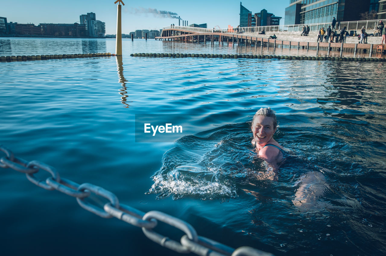 Smiling woman looking at camera and cold water swimming in denmark