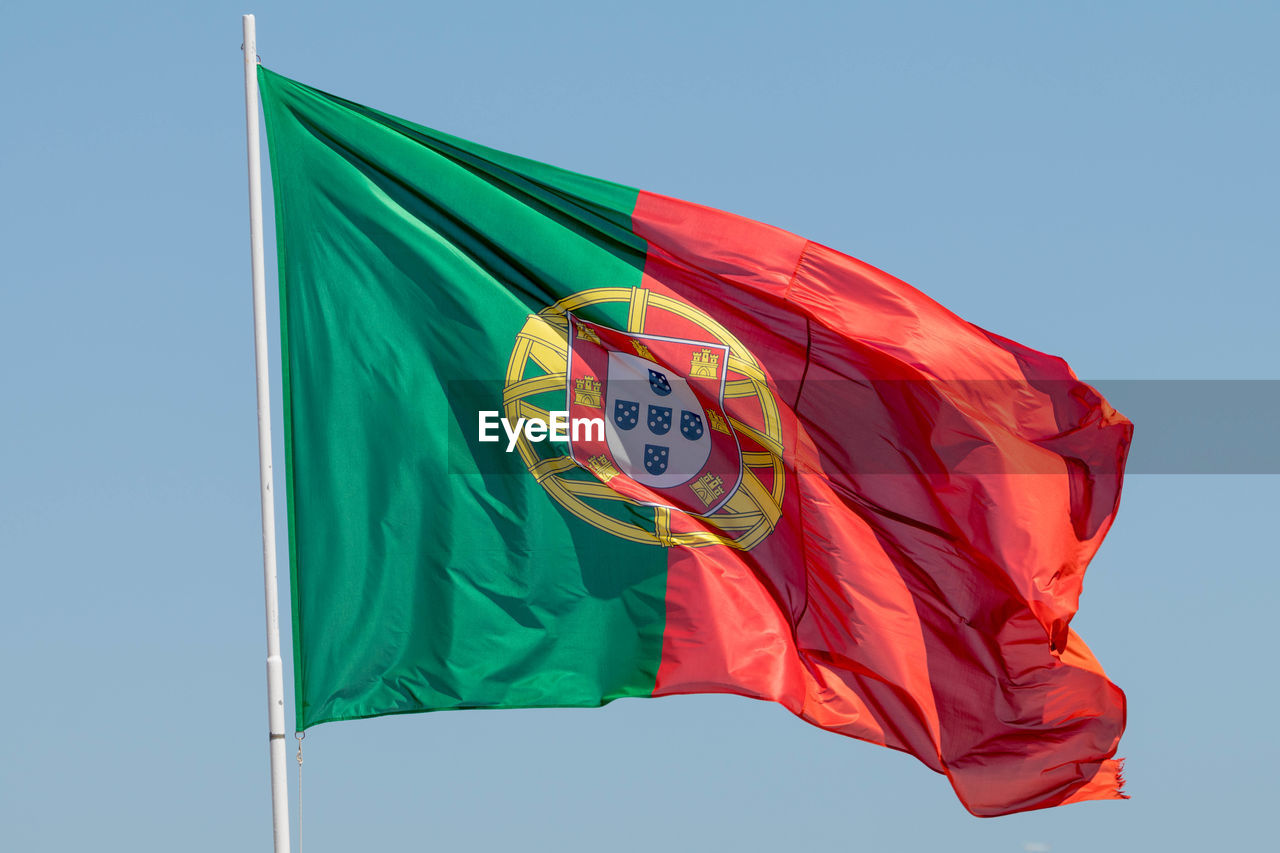 Low angle view of portuguese flag against sky