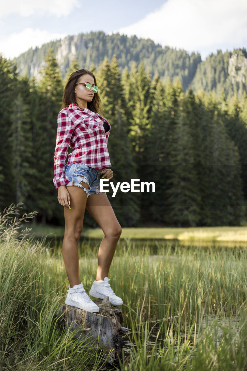 Full length of fashionable young woman standing on field