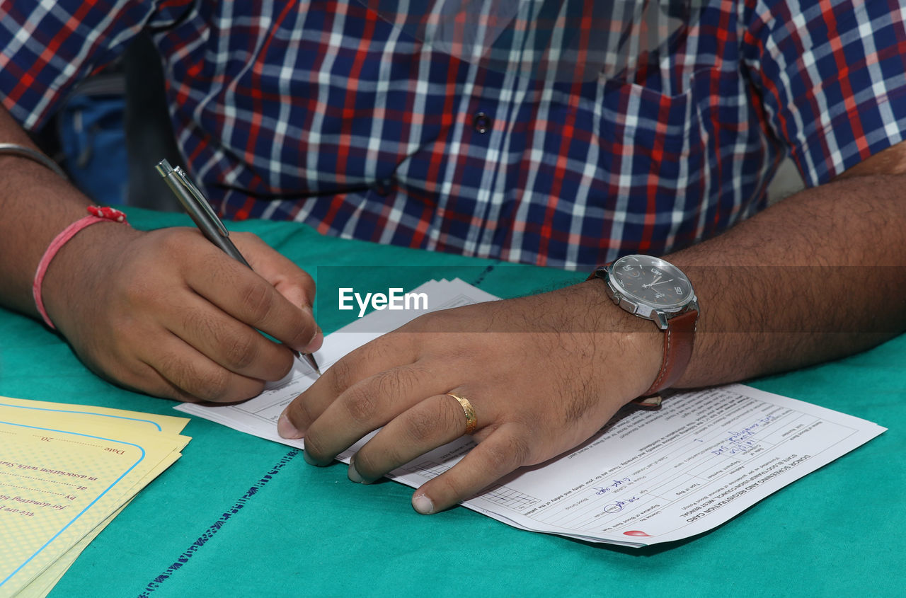 CROPPED IMAGE OF MAN HOLDING PAPER WITH TEXT